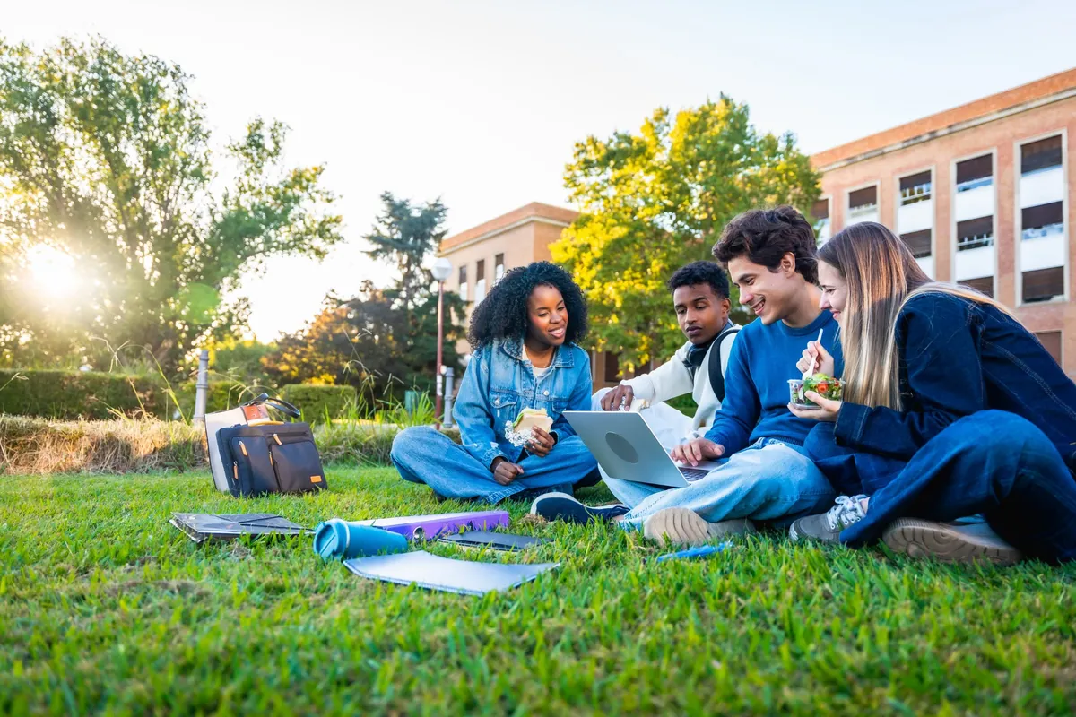 Students working on laptops on a campus lawn